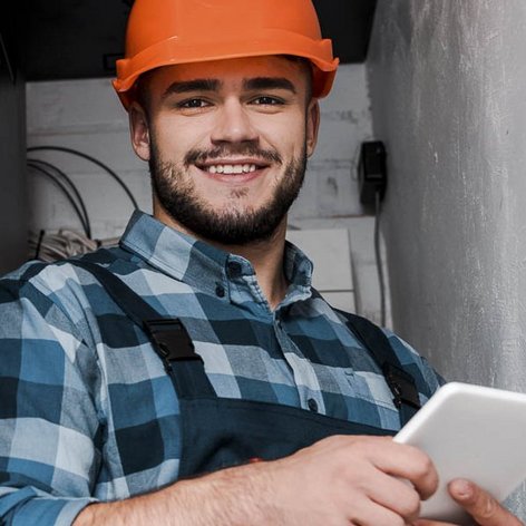 Ein Elektroniker der in einem Serviceraum ein Tablet bedient